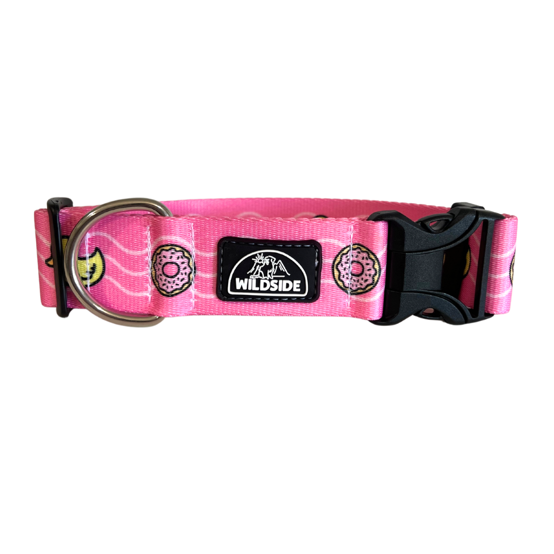 A pink dog collar with a pattern featuring duck and donut graphics, and the brand 'Wildside' displayed.