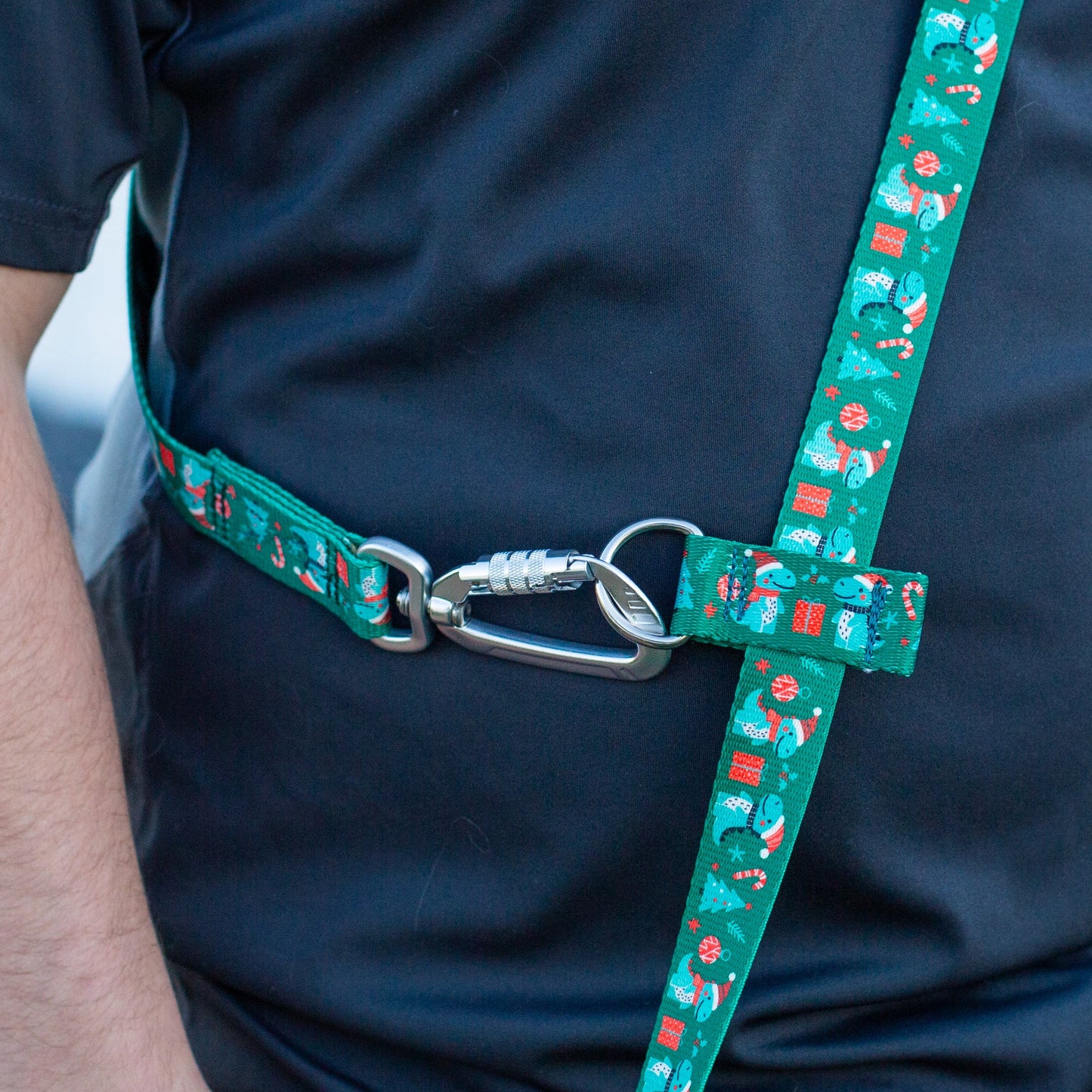 Person wearing a black shirt with a green patterned dog leash over their shoulder.