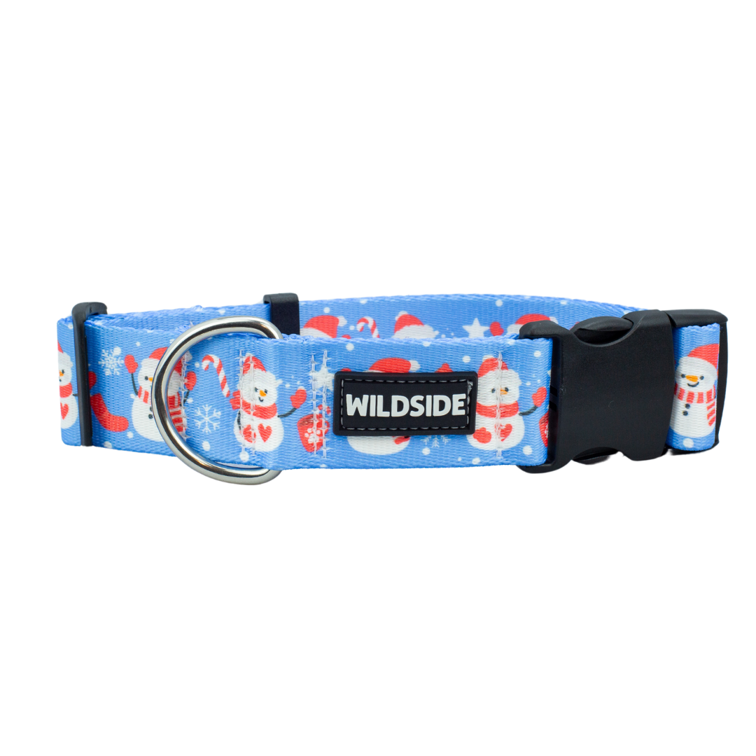 A blue dog collar with a Christmas-themed pattern featuring snowmen and the brand name 'wildside' on a tag.